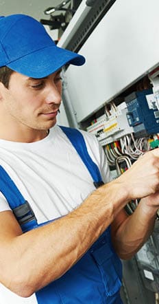 Young adult electrician builder engineer screwing equipment in fuse box
